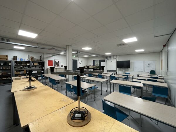 Lokaal aan de Niels Bohrweg ingericht als modern leslokaal met tafels, stoelen, whiteboards en technische apparatuur.